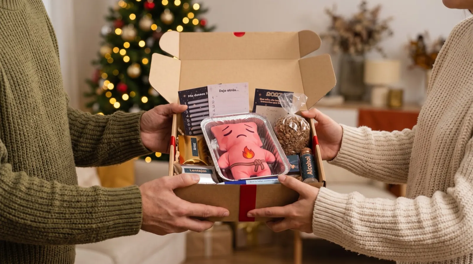 Dos personas se entregan el kit para quemar el año viejo como regalo de Navidad, junto al árbol